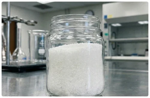 Jar of white xylitol crystals in a laboratory, the sugar alcohol used in DentaBiome chewable tablets